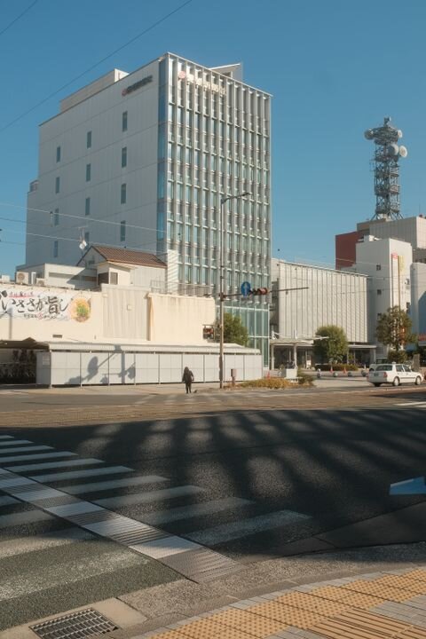 Modern urban streetscape with an office building and crosswalk in daylight.