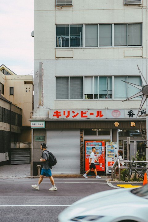 A couple of people crossing a street in front of a building