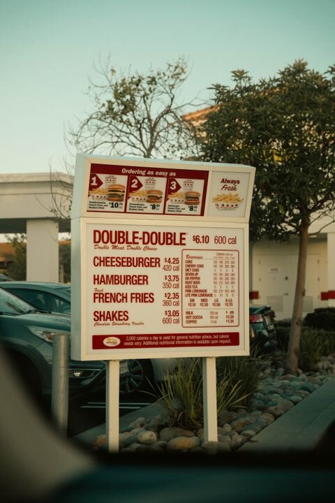 Drive-thru menu sign at a fast food restaurant with visible car.