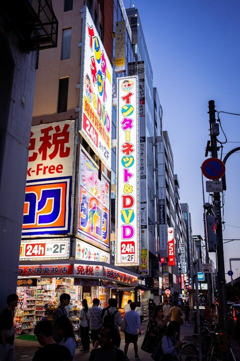 Brightly lit street with shops and signs at dusk