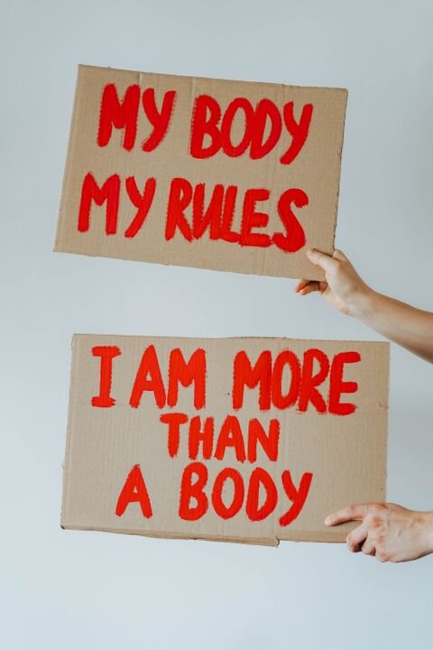 Hands holding cardboard signs with empowering feminist messages.