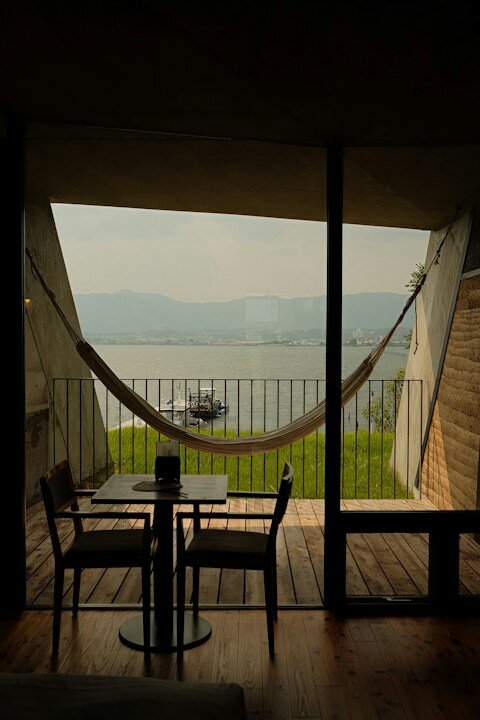 Balcony with table, chairs, and hammock overlooking water