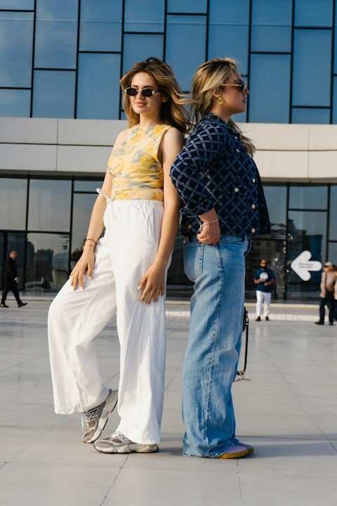 Two young women standing back to back outdoors